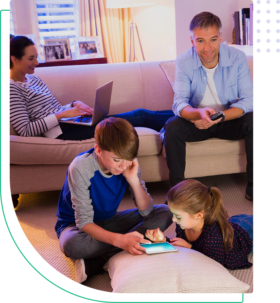Two children using a tablet while parents watch.